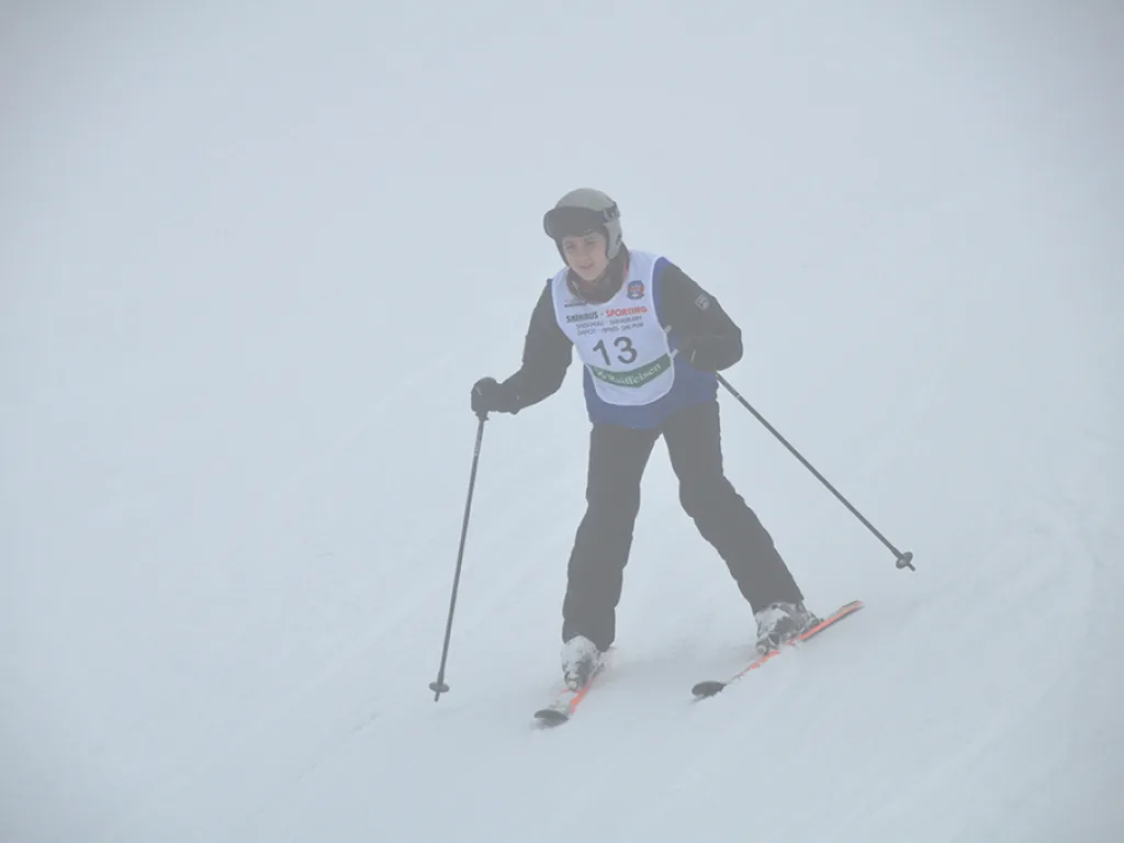 Skifahrer mit Startnummer 13 fährt talwärts.